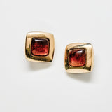 Gold square earrings with brown gemstones on a white background