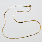 Full view of vintage gold-tone herringbone chain necklace laid in gentle curves with spring ring clasp