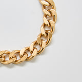 Close-up of vintage Monet gold chain bracelet showing polished curb links and textured edge detailing.