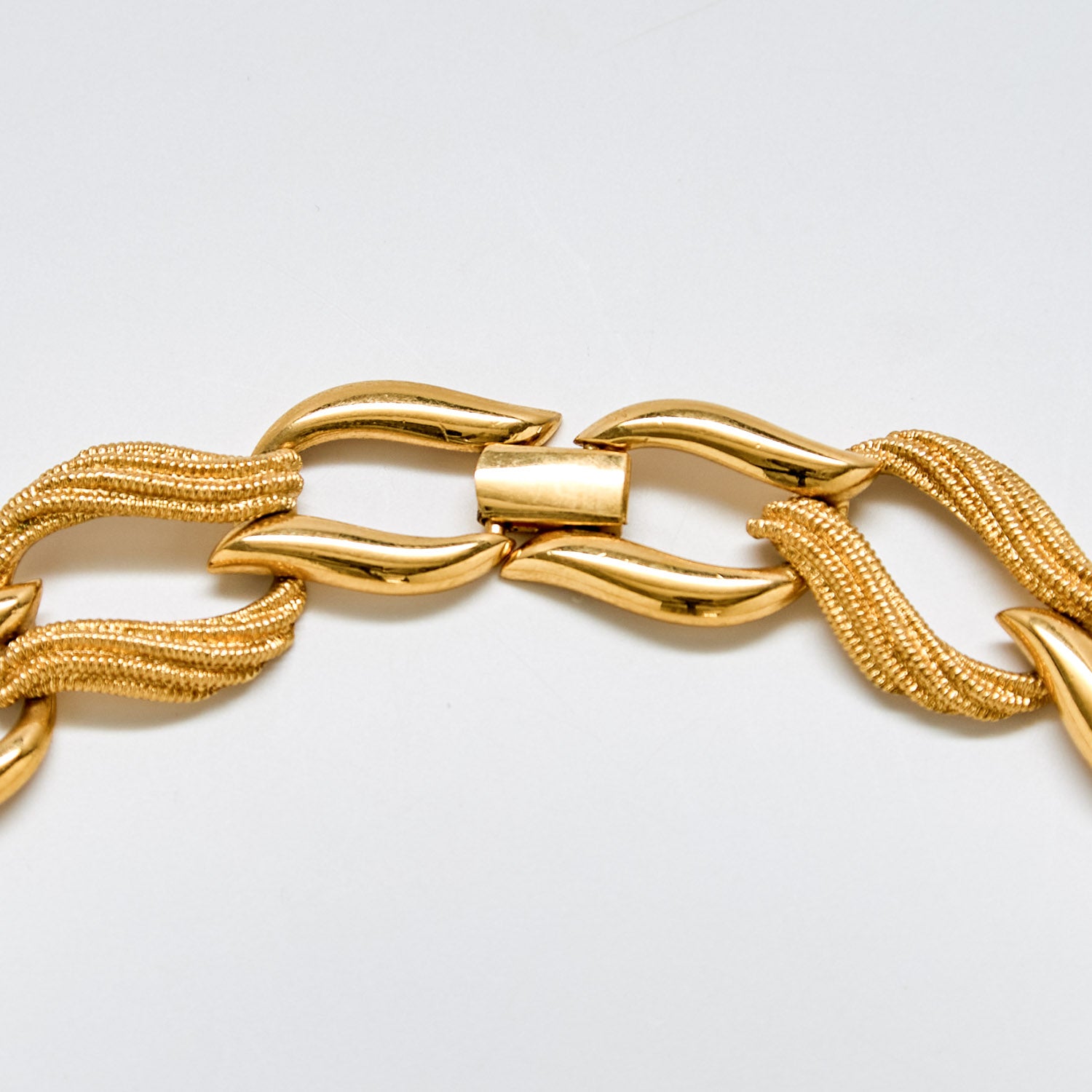 Detail of vintage Napier gold necklace clasp and smooth sculptural links with fine mesh texture.