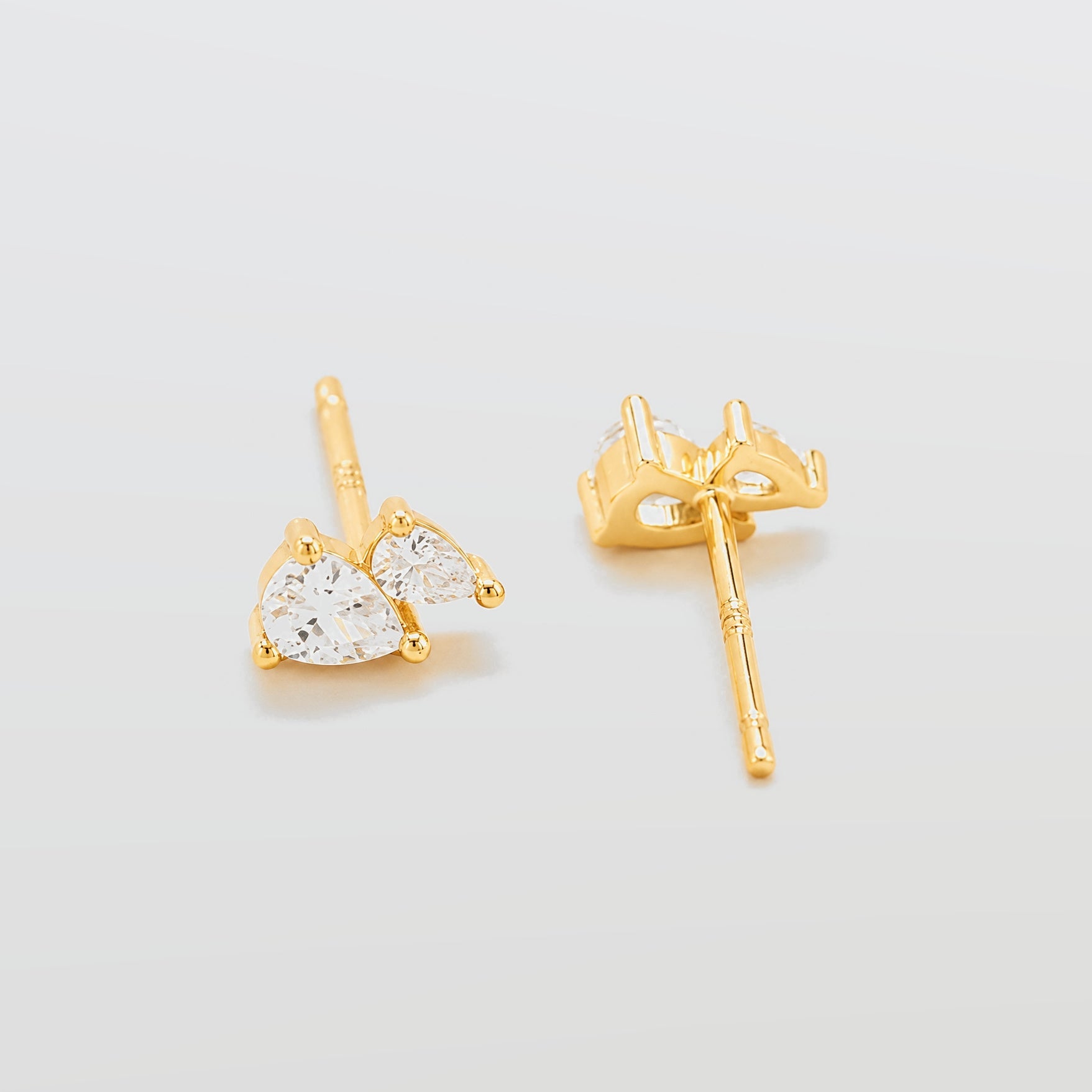 Gold heart-shaped earrings on a light gray background