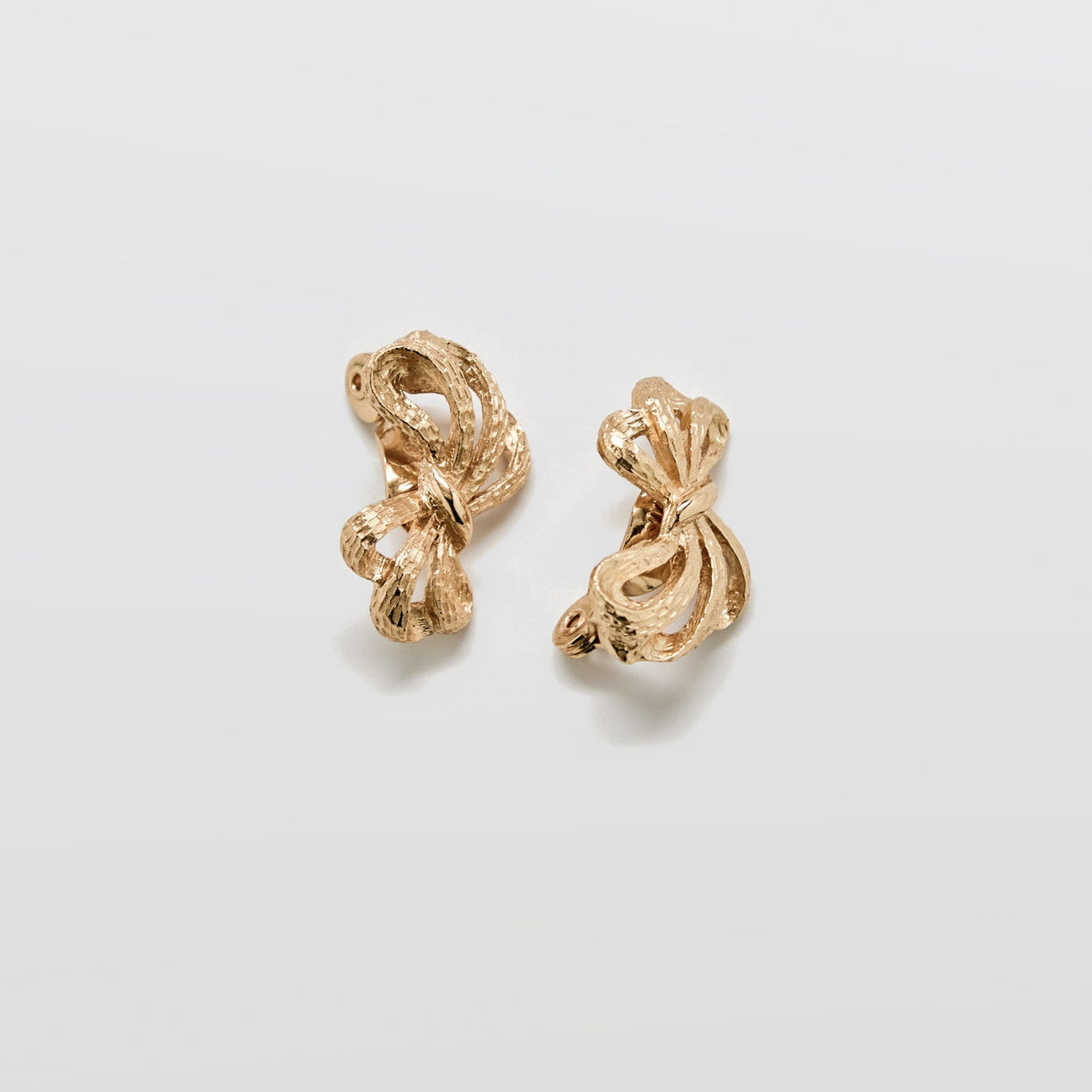 Pair of gold earrings on a light gray background