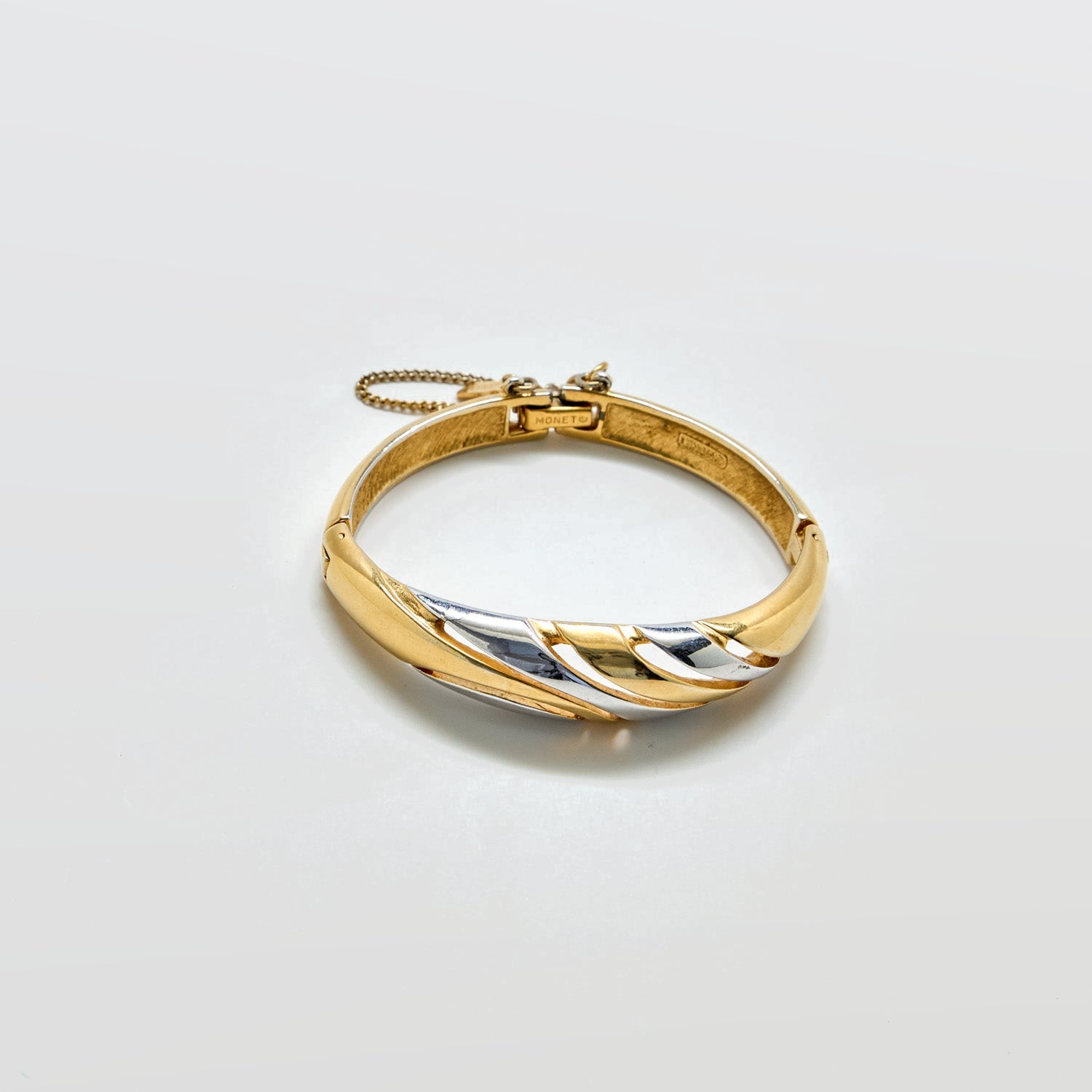 Gold bracelet with a two-tone design on a light gray background