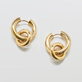 Gold interlocking hoop earrings against white background with removable charm detail in polished stainless steel, modern statement hoop design.