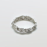 Silver ring with textured design on a light gray background