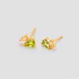 Gold earrings with green gemstones on a light gray background