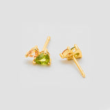 Gold earrings with green gemstones on a light gray background