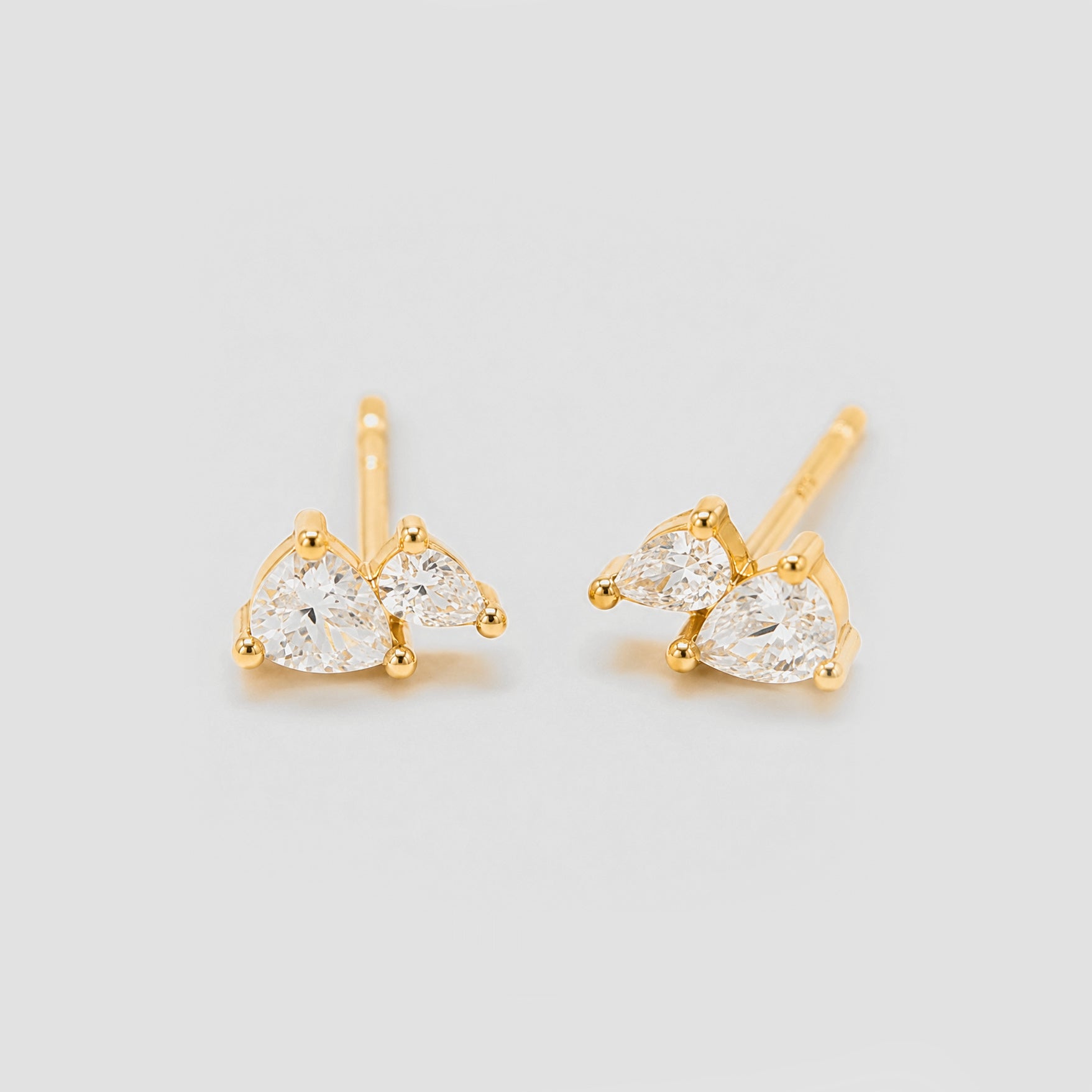 Gold earrings with clear gemstones on a light gray background