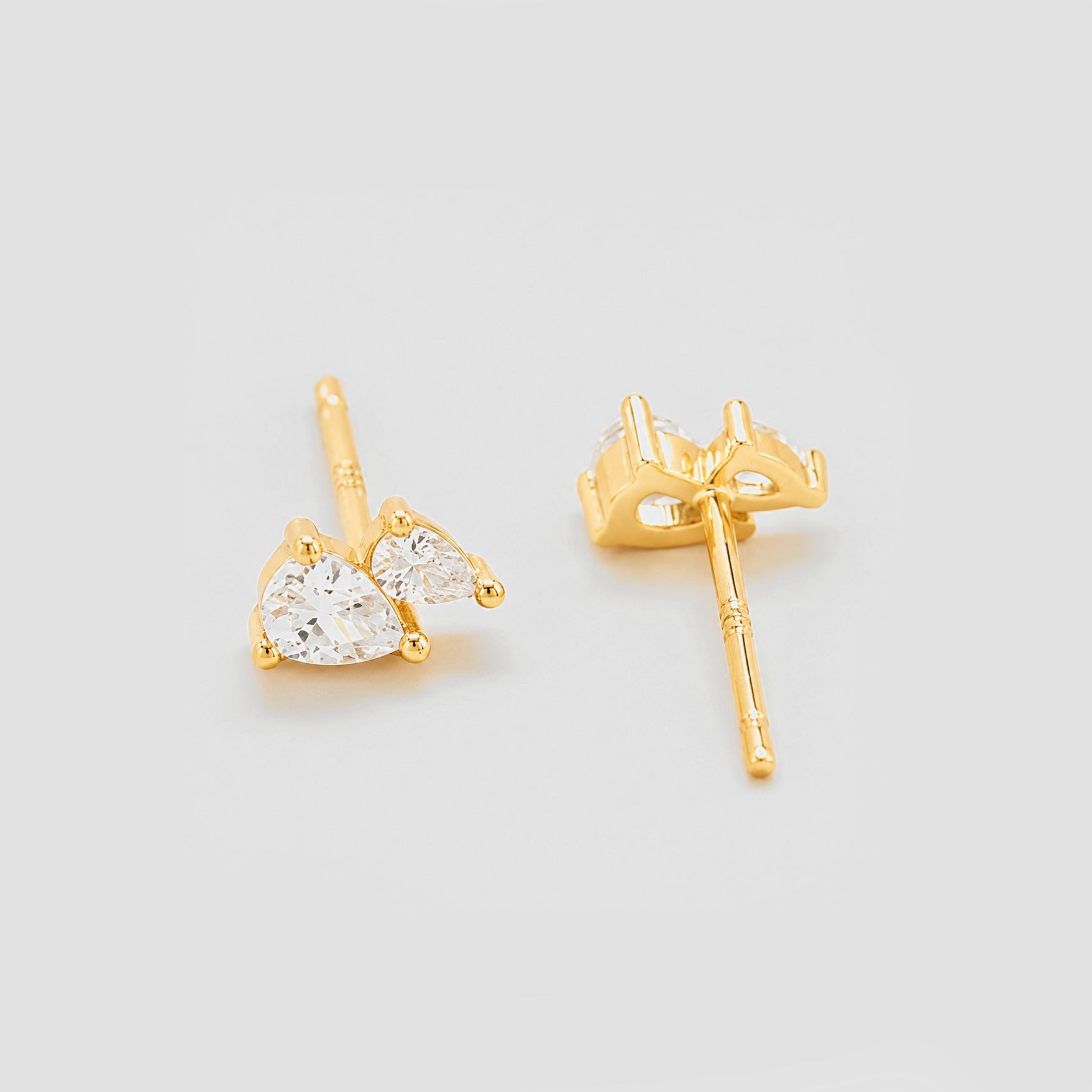 Gold heart-shaped earrings on a light gray background