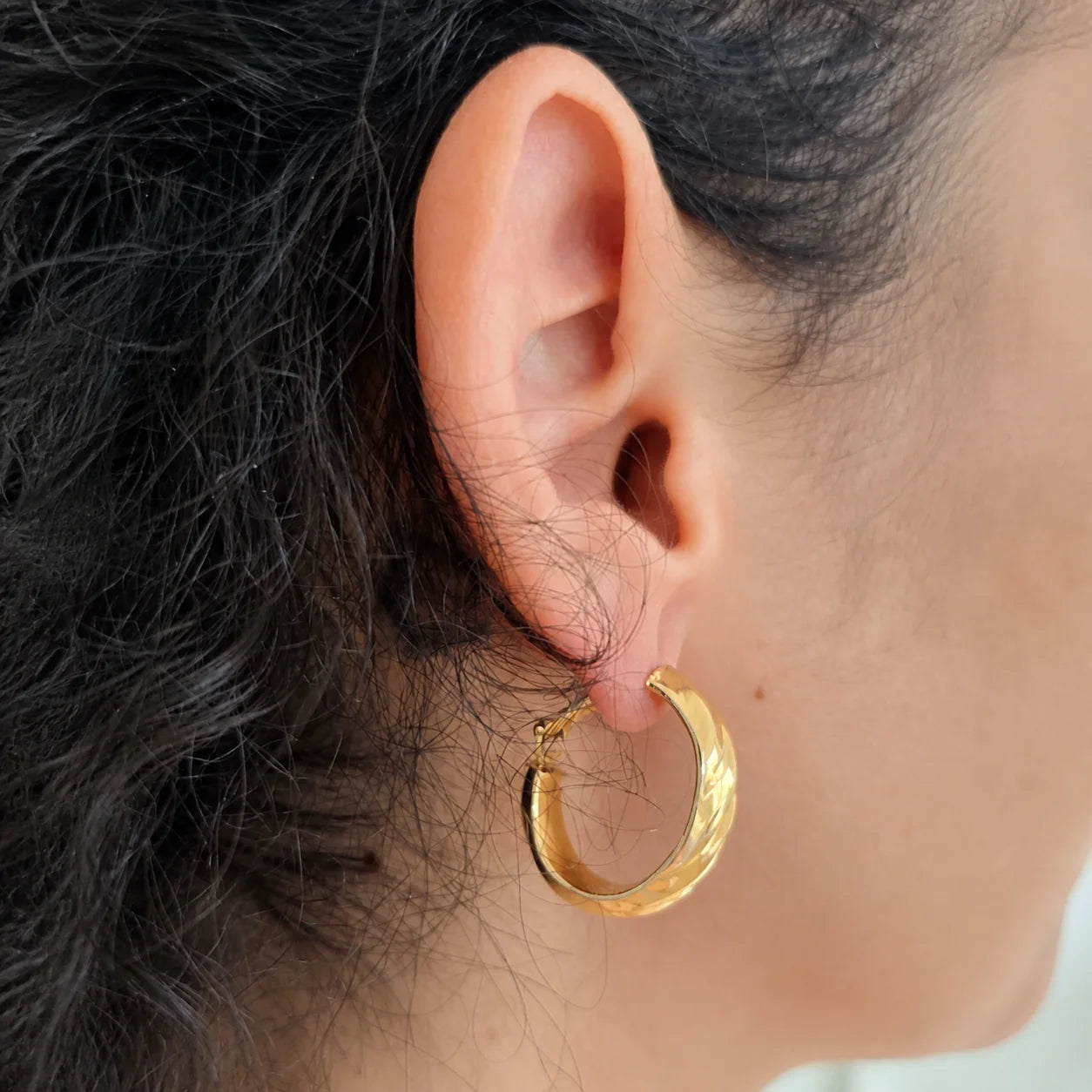 Model wearing Vintage Monet gold-tone twist hoop earring, rear three-quarter view