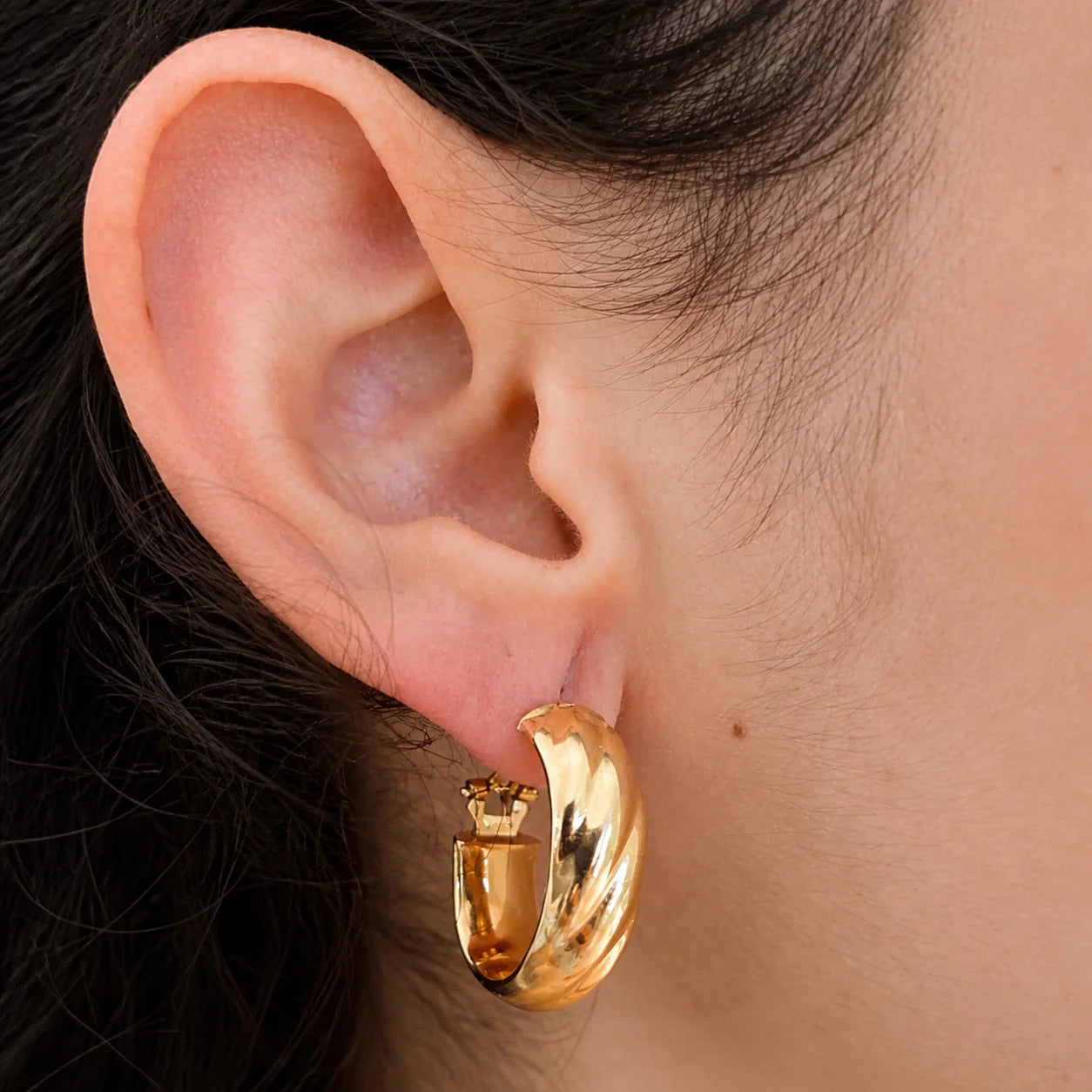 Model wearing Vintage Monet gold-tone twist hoop earring, close-up