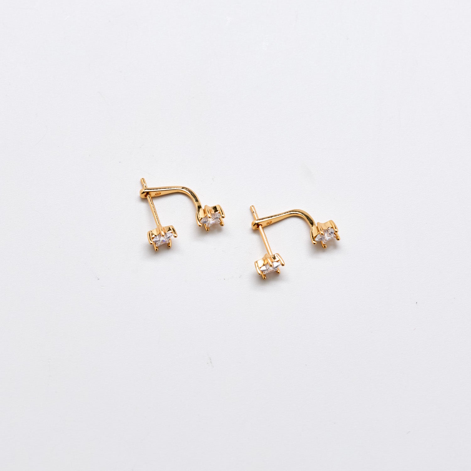 Gold cubic zirconia double stud ear jacket earrings with curved crystal accent on white background.
