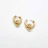 Polished gold stainless steel hoop earrings against white background featuring detachable interlocking loop charm, modern sculptural jewelry design.