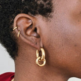 Close up of model wearing gold interlocking hoop earrings with removable charm, chunky gold statement hoop earrings in polished stainless steel.