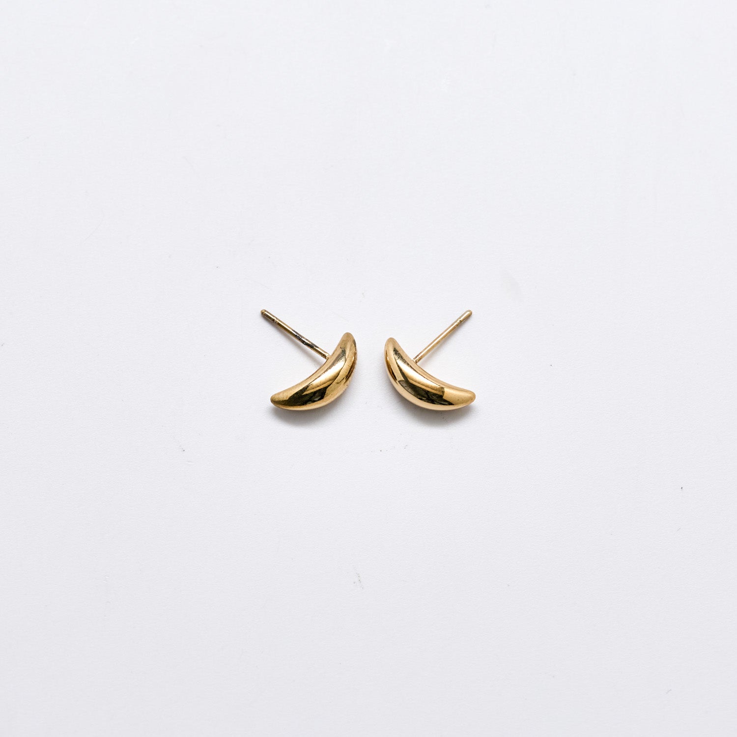 Pair of small curved gold stud earrings with a smooth polished finish and post backs against a white background