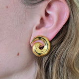 Gold spiral earring worn by a person with blonde hair.