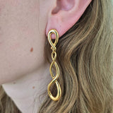 Gold spiral earring worn by a person with blonde hair.