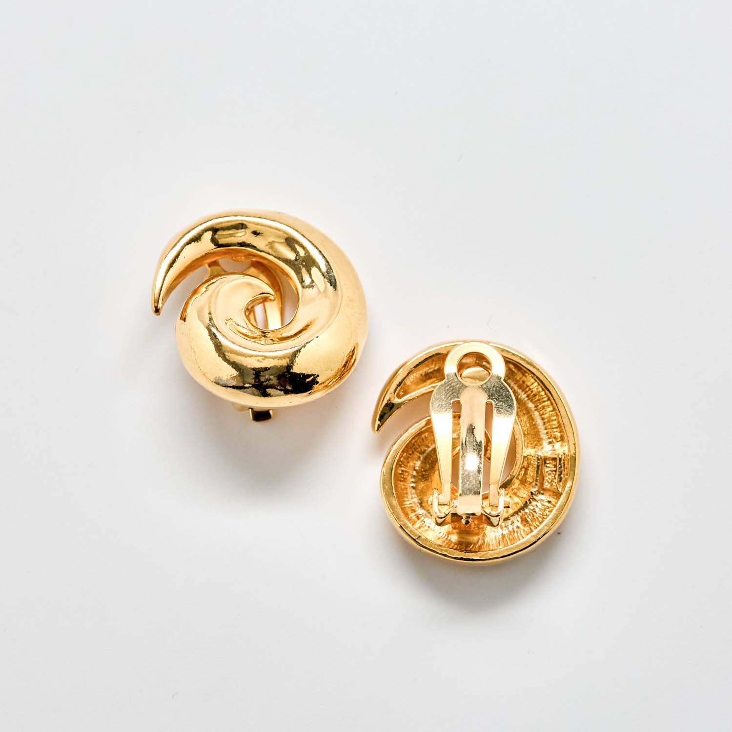 Pair of gold spiral earrings on a light gray background