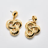 Gold knot drop earrings on a light gray background