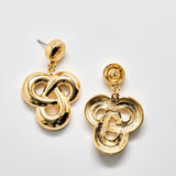 Pair of gold drop earrings on a light gray background