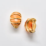 Gold earrings with peach-colored stones on a light gray background