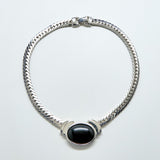 Silver bracelet with a black stone on a light gray background