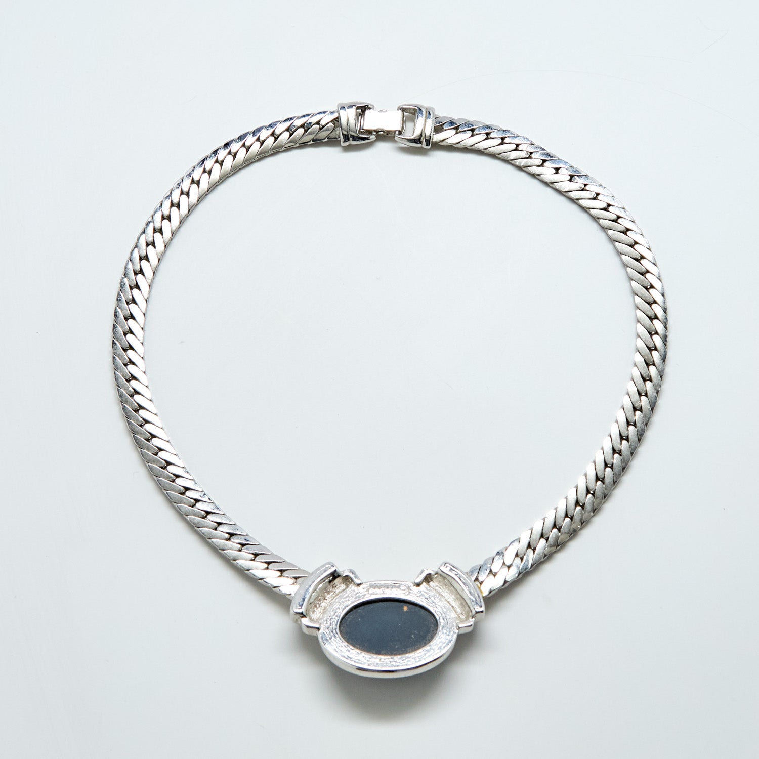 Silver chain necklace with a black stone on a light gray background