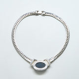 Silver chain necklace with a black stone on a light gray background