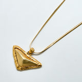 Gold triangle pendant necklace on a light gray background