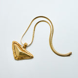 Gold necklace with a triangular pendant on a light gray background