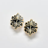 Pair of black and gold decorative earrings on a light gray background