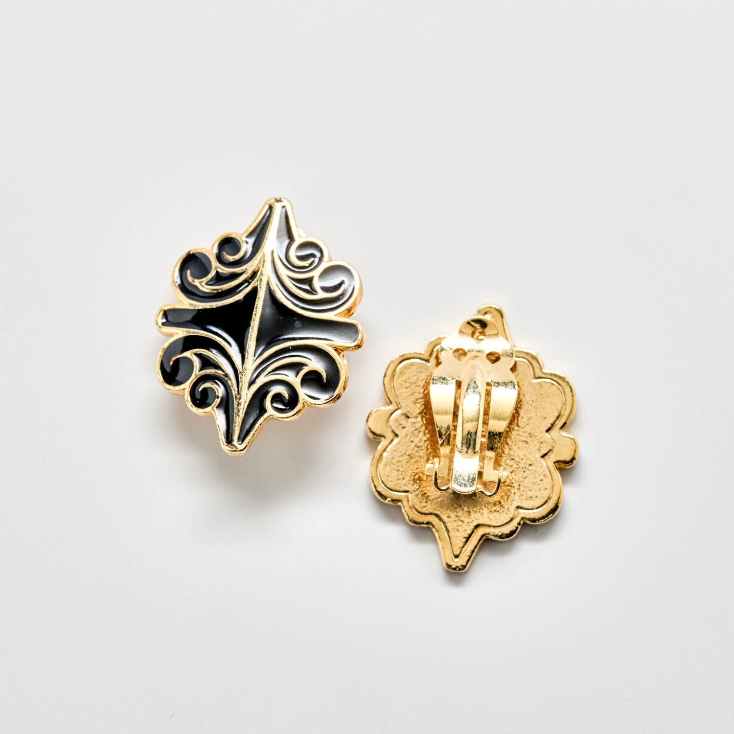 Gold and black decorative earrings on a light gray background