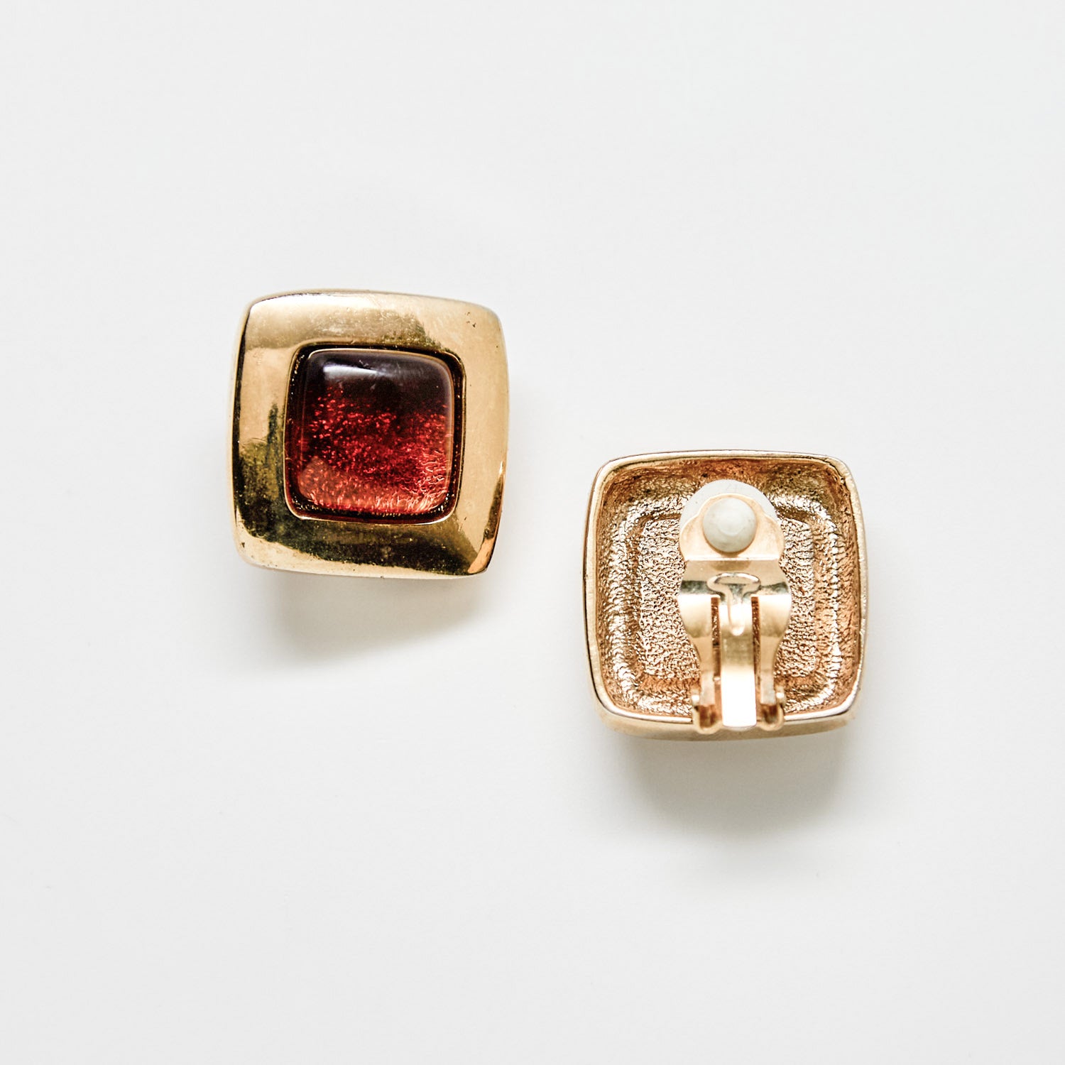 Gold earrings with a brown gemstone on a white background