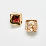 Gold earrings with a brown gemstone on a white background