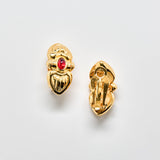 Gold earrings with a red gemstone on a light gray background