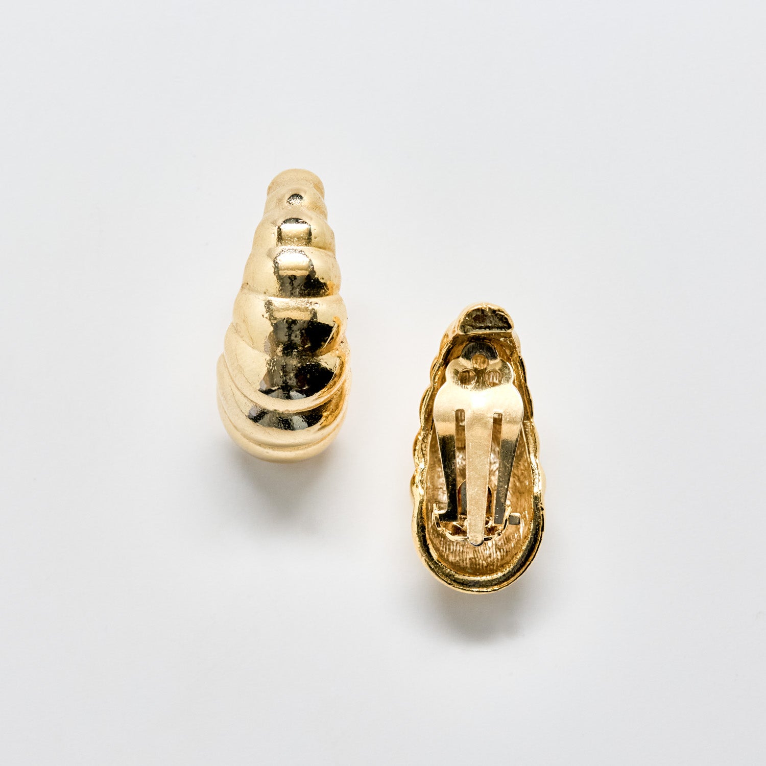 Gold shell-shaped earrings on a light gray background
