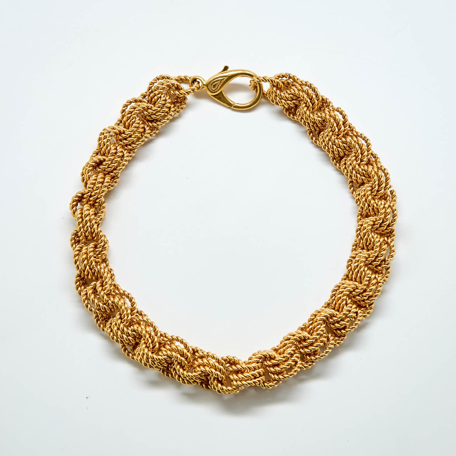 Gold braided bracelet on a white background