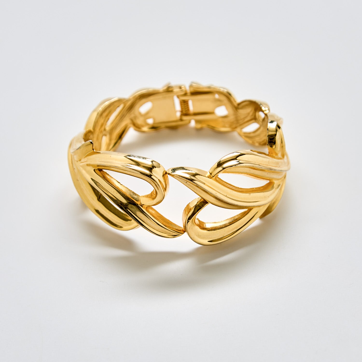 “Full view of vintage gold sculptural bracelet with wave-like link design and glossy gold finish