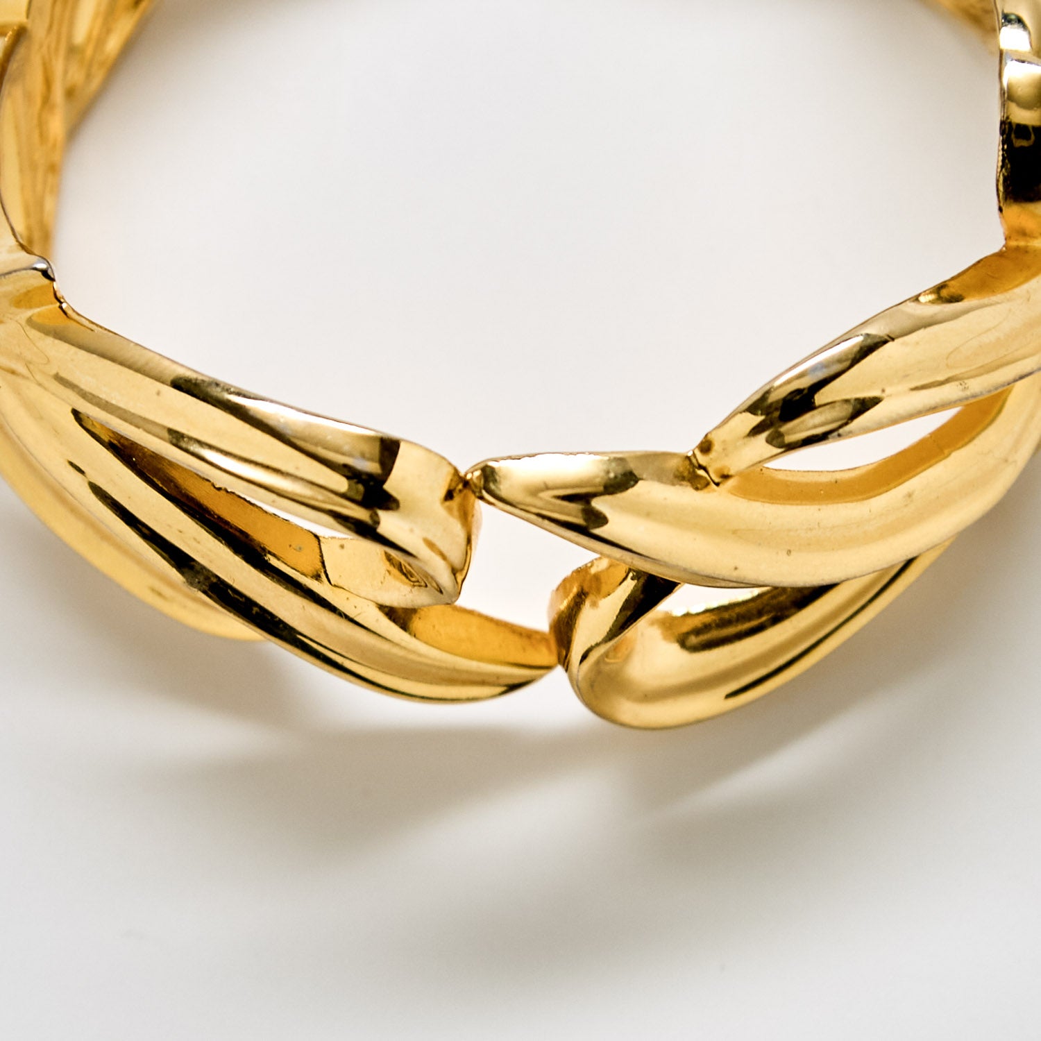 Detailed view of vintage gold-tone bracelet with curved interlocking links and polished finish
