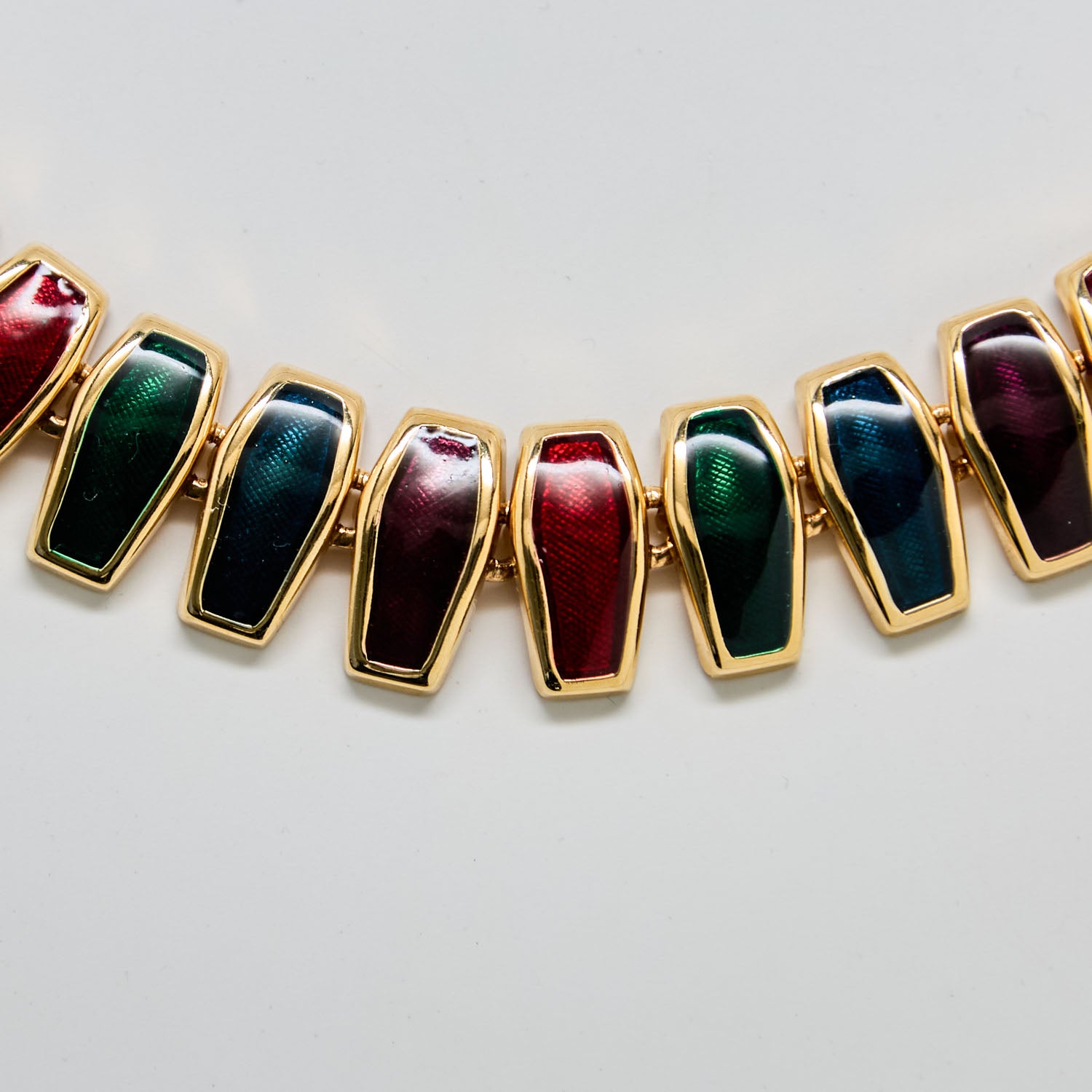 Necklace with gold links and multicolored stones on a light gray background