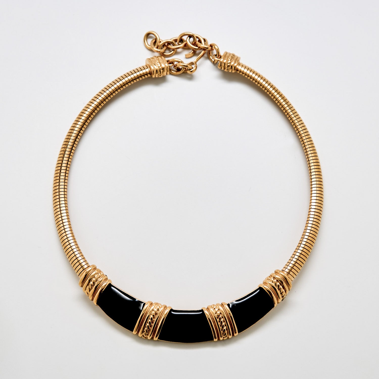 Gold and black necklace on a light gray background