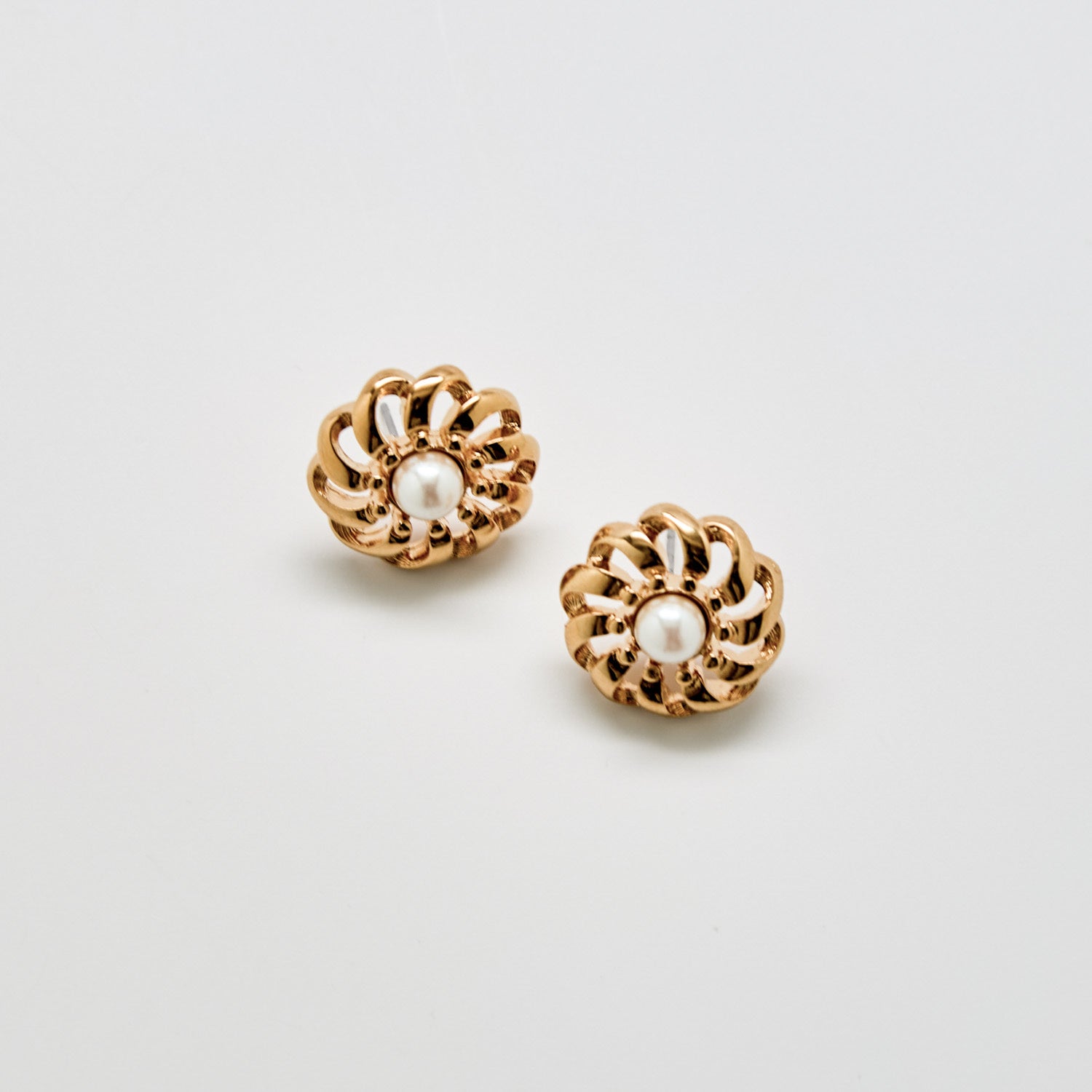 Pair of gold earrings with pearl centers on a light gray background