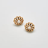 Pair of gold earrings with pearl centers on a light gray background