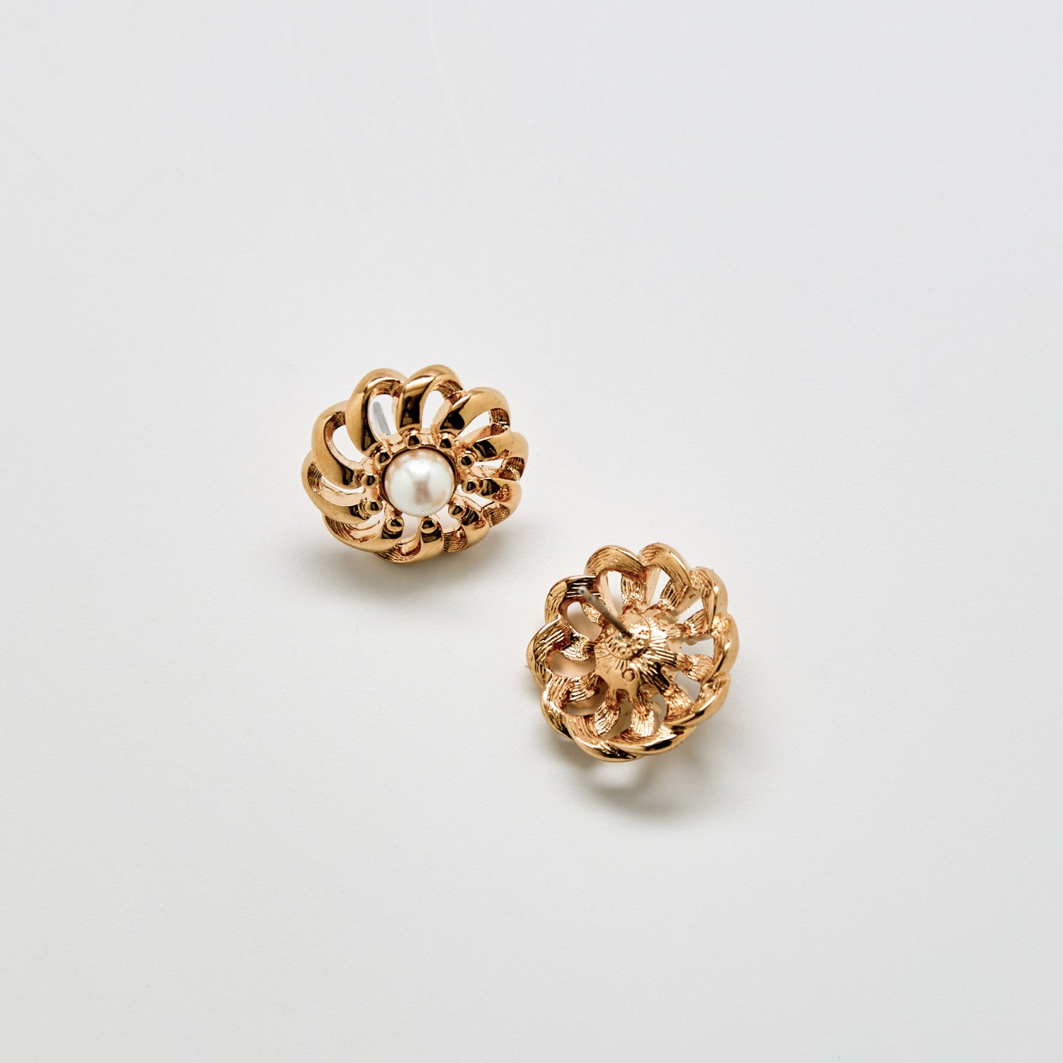 Pair of gold floral earrings on a light gray background