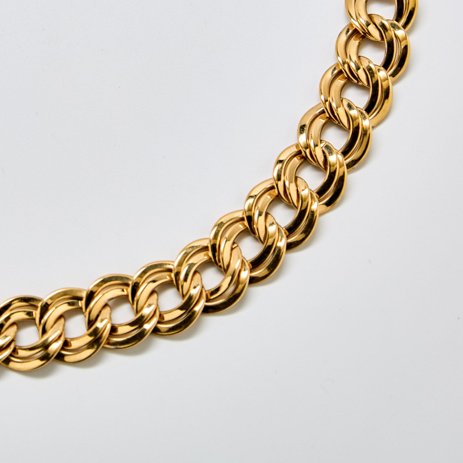 Close-up of vintage Monet double-link chain necklace showing interlocking links and reflective gold surface.