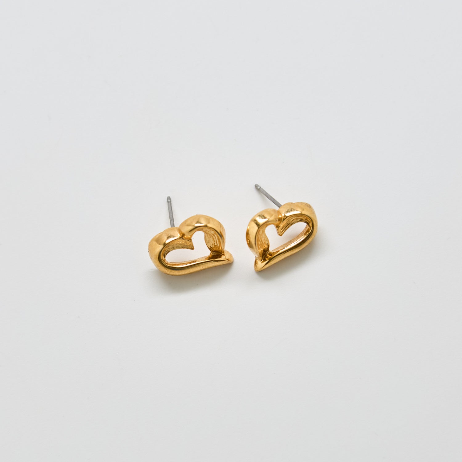 Front view of vintage Monet gold-tone open-heart stud earrings with sculptural design and polished finish.
