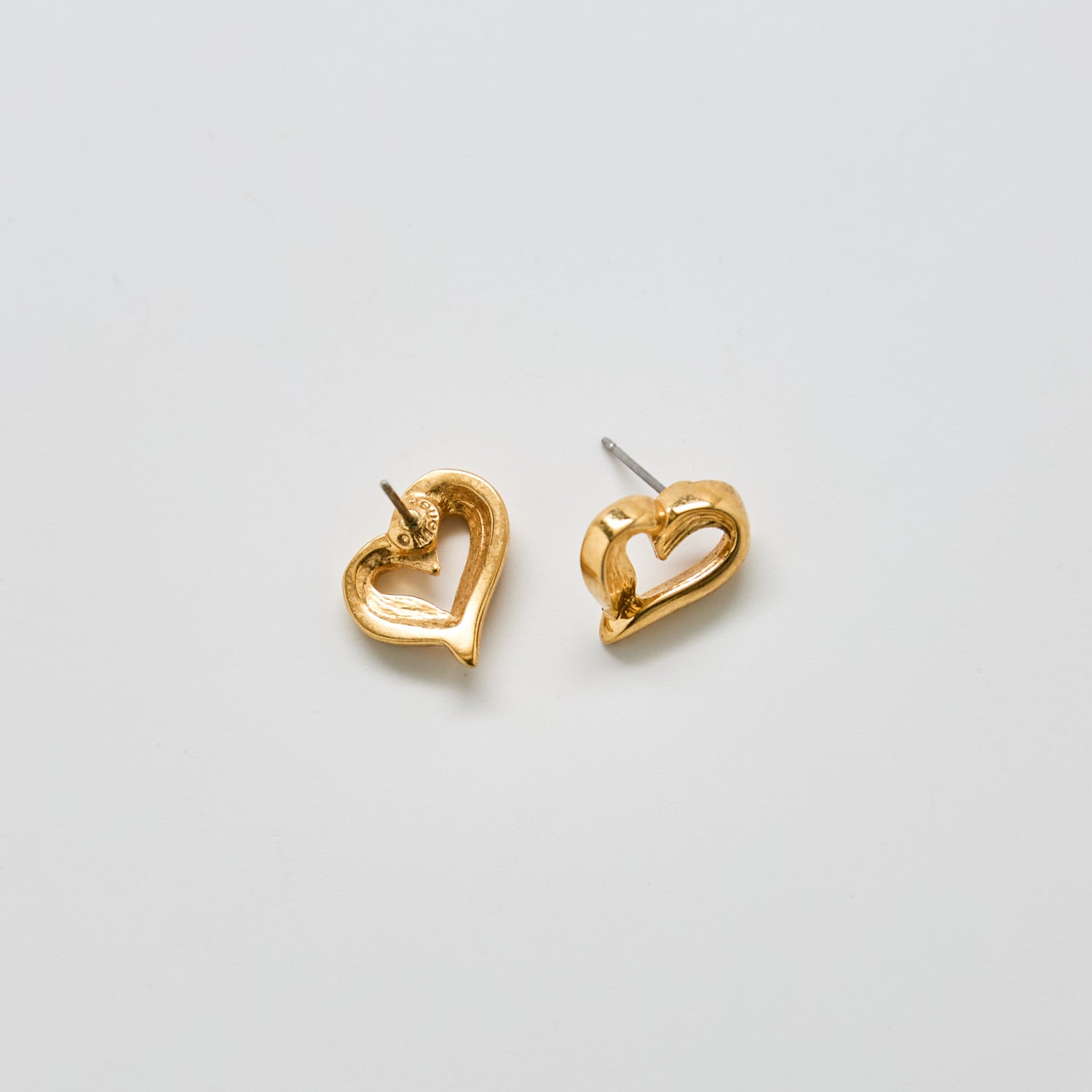 Angled view of vintage Monet gold heart earrings showing post back closure and dimensional open-heart shape.