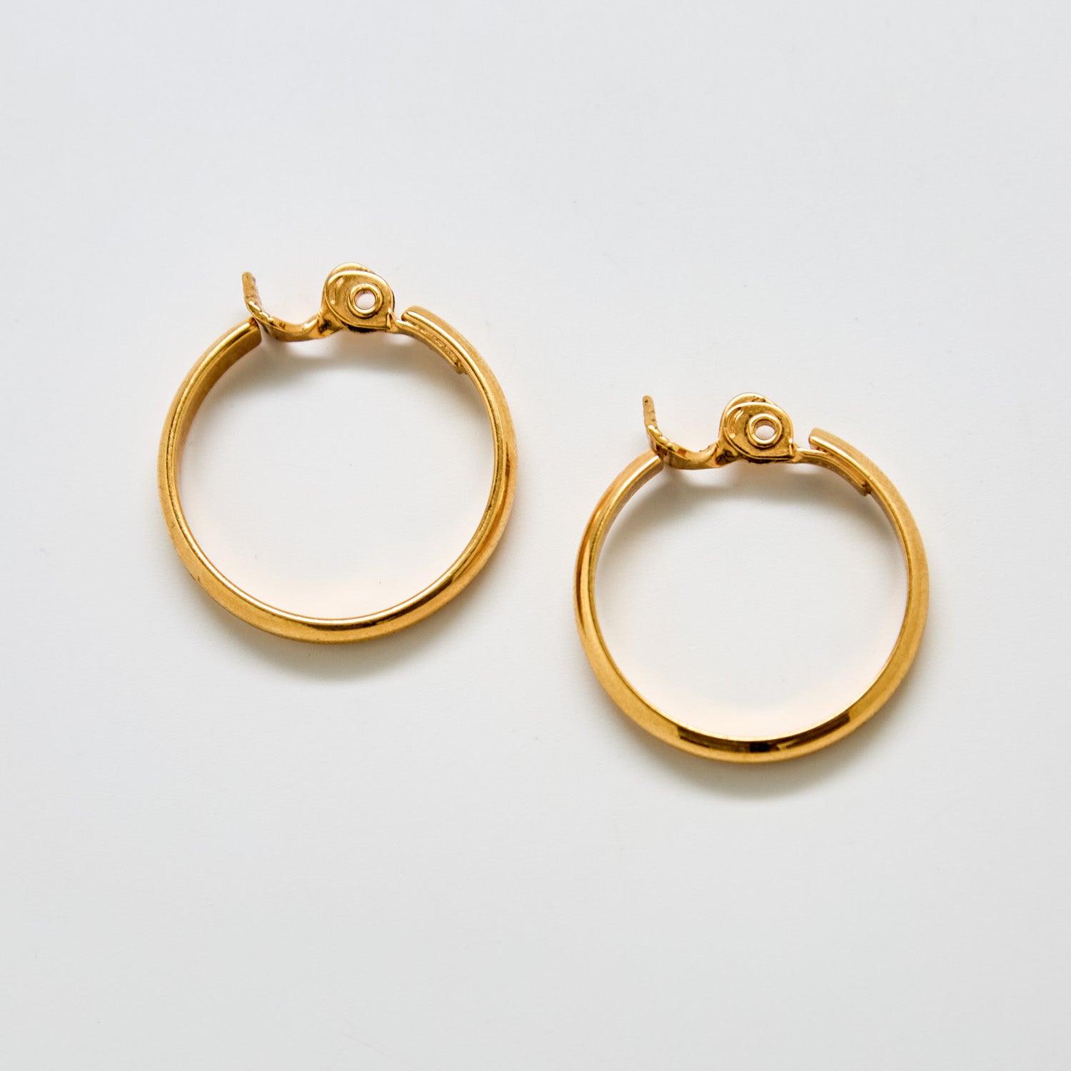 Front view of vintage Monet gold-tone hoop earrings with smooth polished finish and latch-back closure.