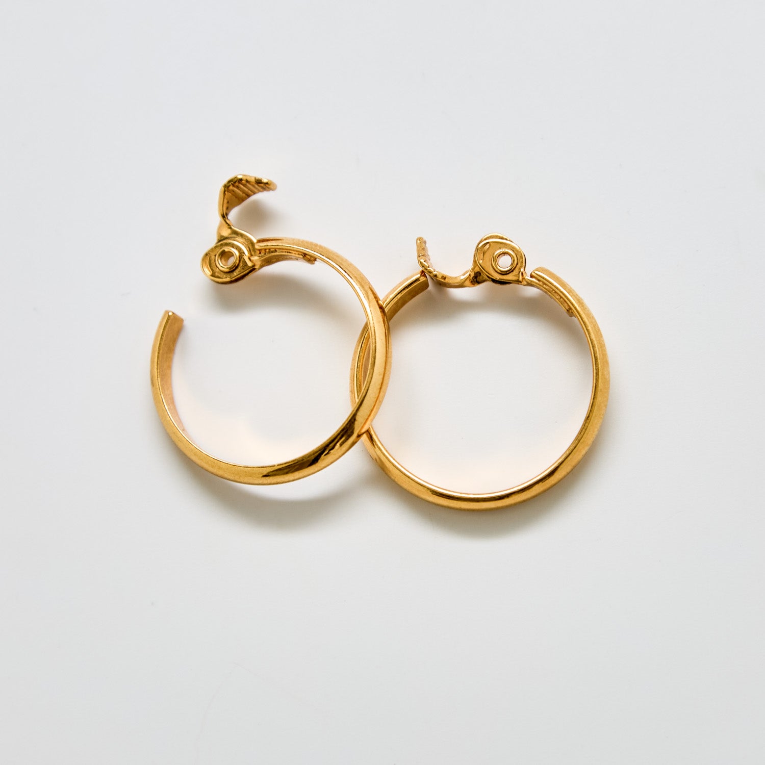 Angled view of vintage Monet gold hoop earrings showing hinge clasp design and circular shape.