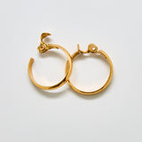 Angled view of vintage Monet gold hoop earrings showing hinge clasp design and circular shape.